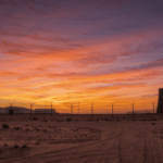 Base militare remota nel deserto con torre misteriosa all'orizzonte